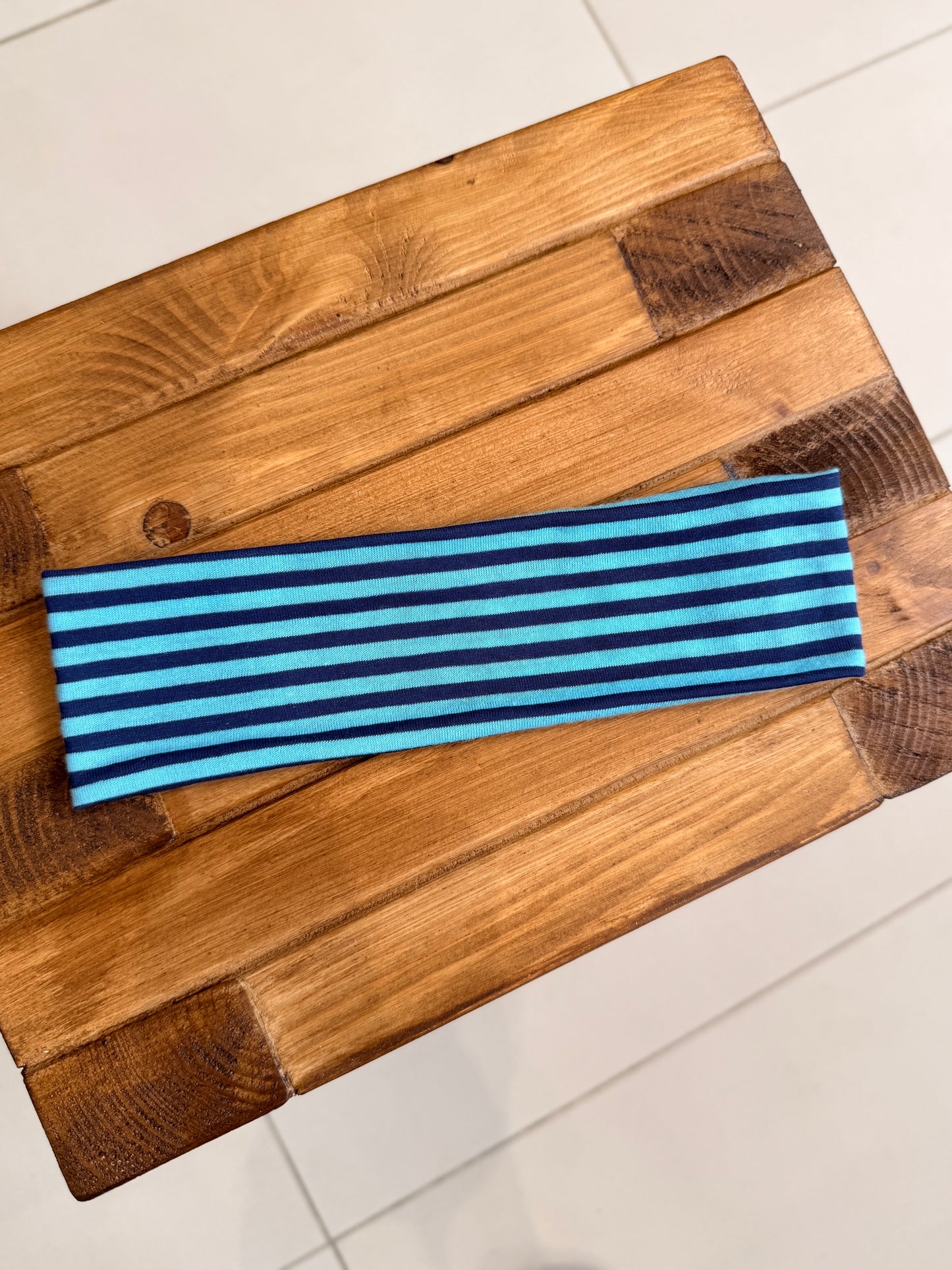 Blue and baby blue striped headband on a wooden surface