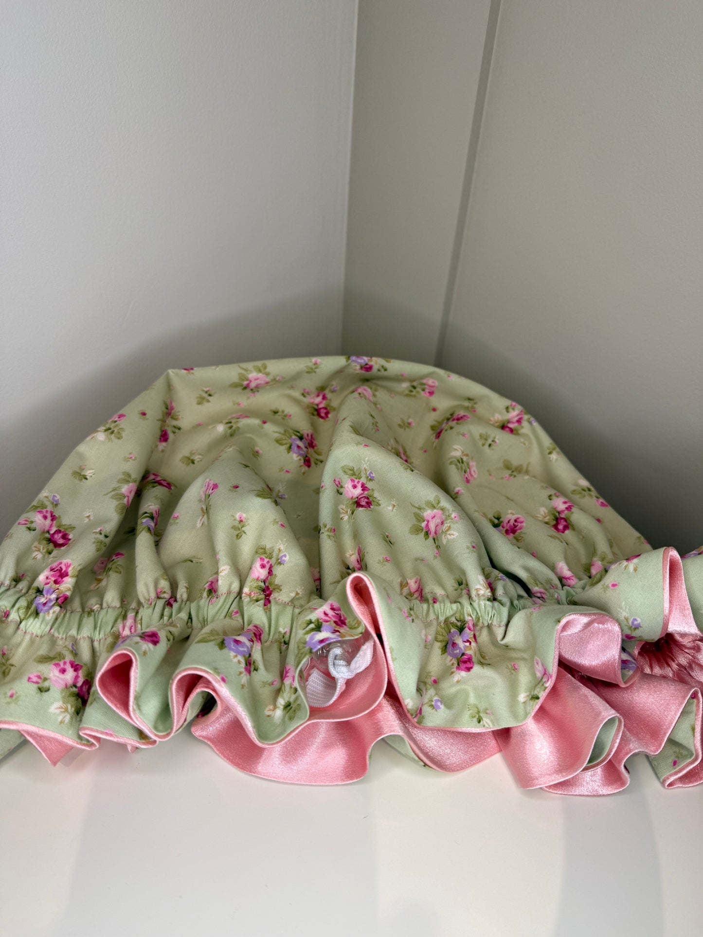 Floral-patterned bonnet with pink high quality satin, showing the adjustable toggle on a white background