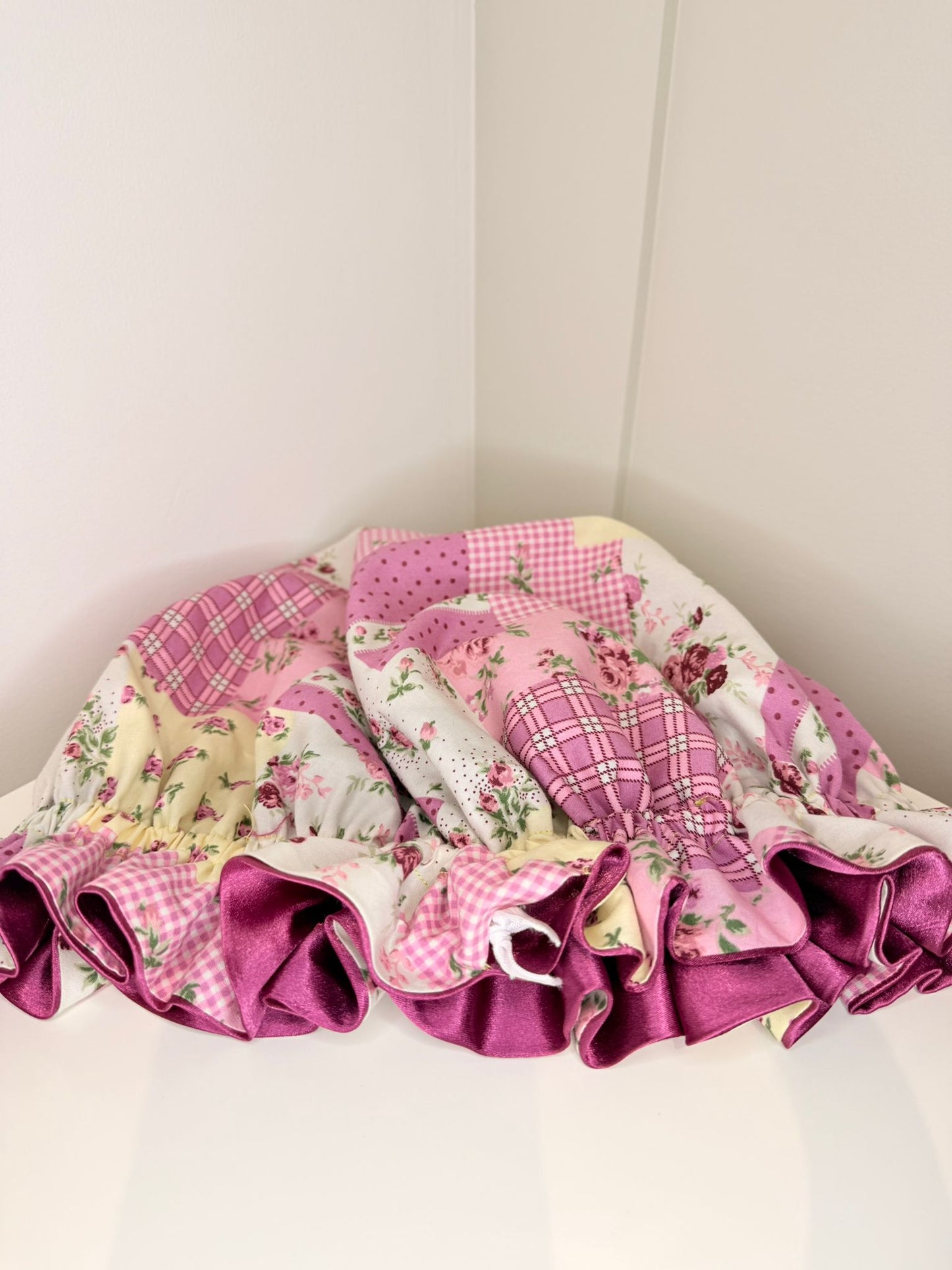 Pink and floral patwork fabric bonnet with ruffled edges on a white background