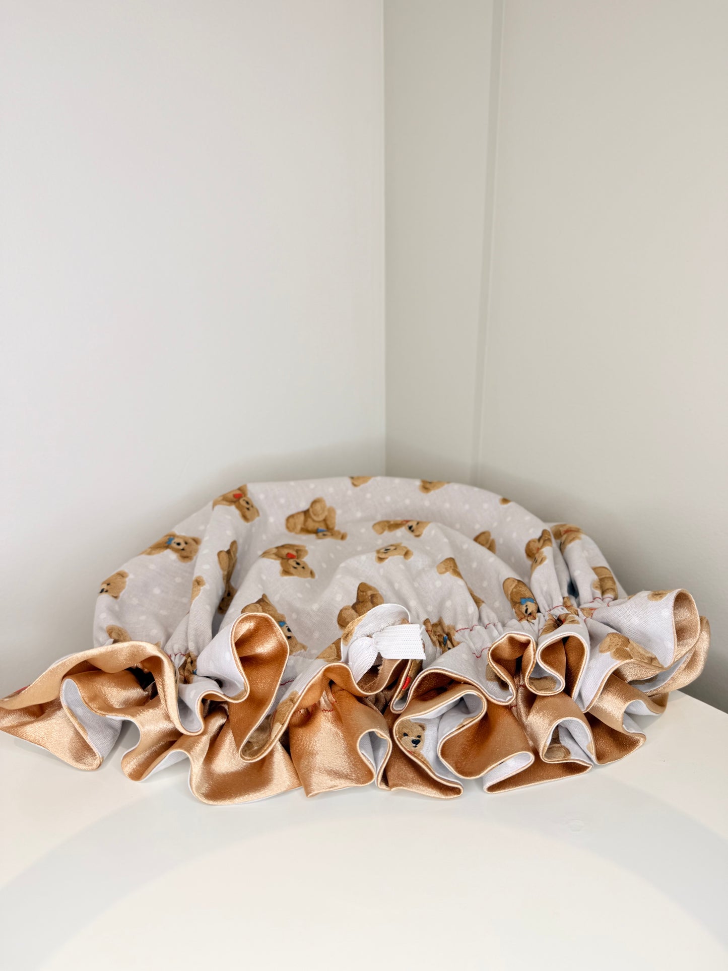 Teddy bear design satin bonnet on a mannequin head in a room with a lamp 