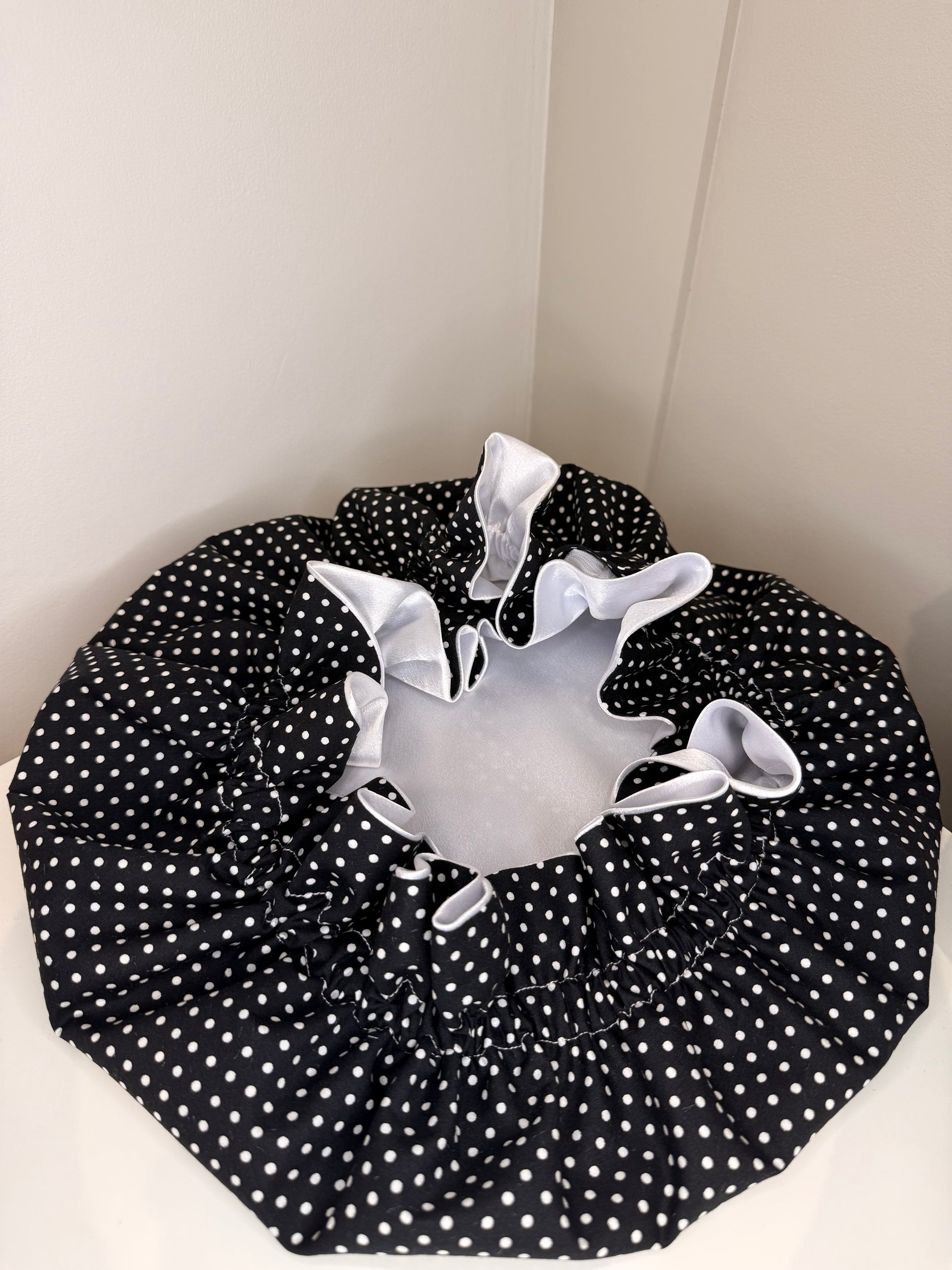 White with a black polka dot bonnet open showing white satin on a white background