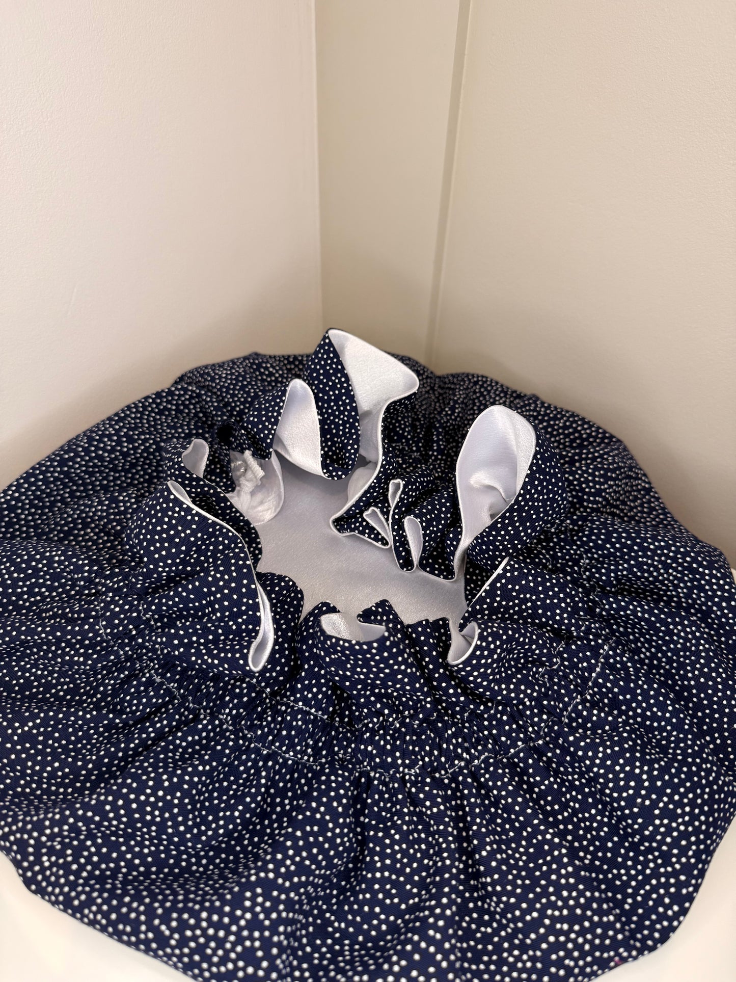 Navy blue bonnet with small white dots replicating stars exposing the white luxurious satin 