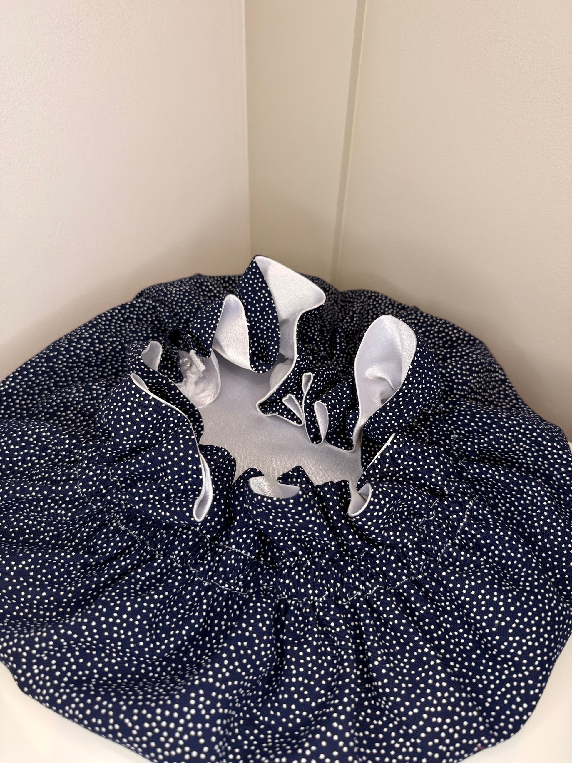 Navy blue bonnet with small white dots replicating stars exposing the white luxurious satin 