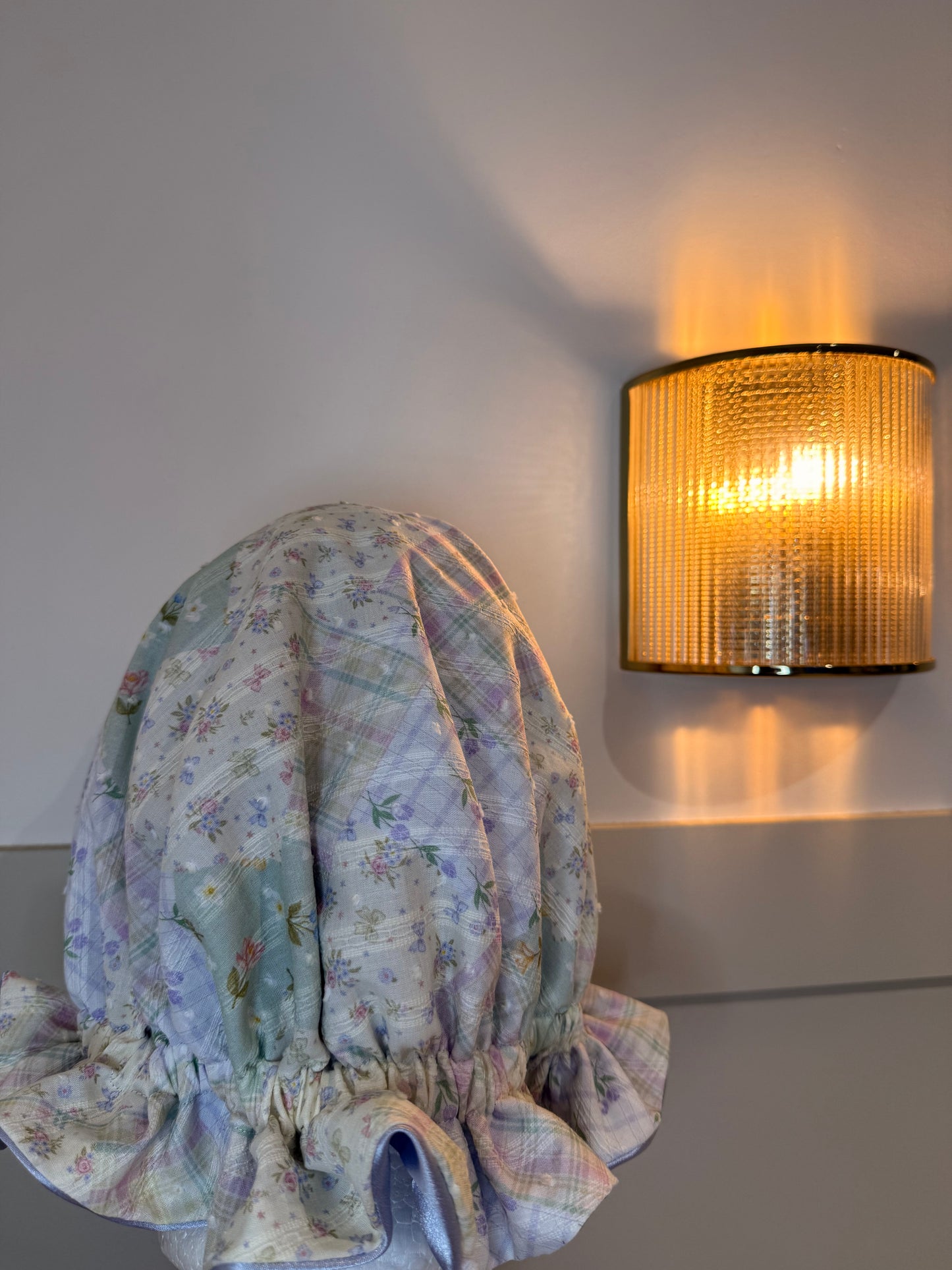 Decorative floral-patterned bonnet next to a wall-mounted light fixture. Made in the UK.