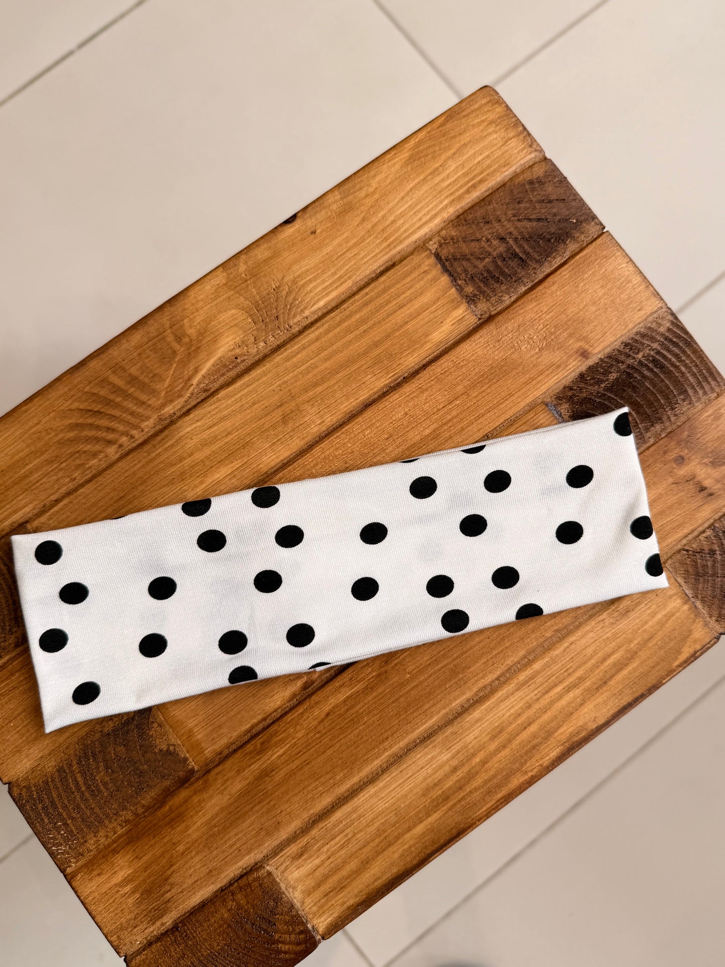 White headband with black polka dots on a wooden surface