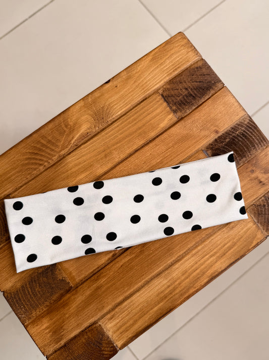 White headband with black polka dots on a wooden surface