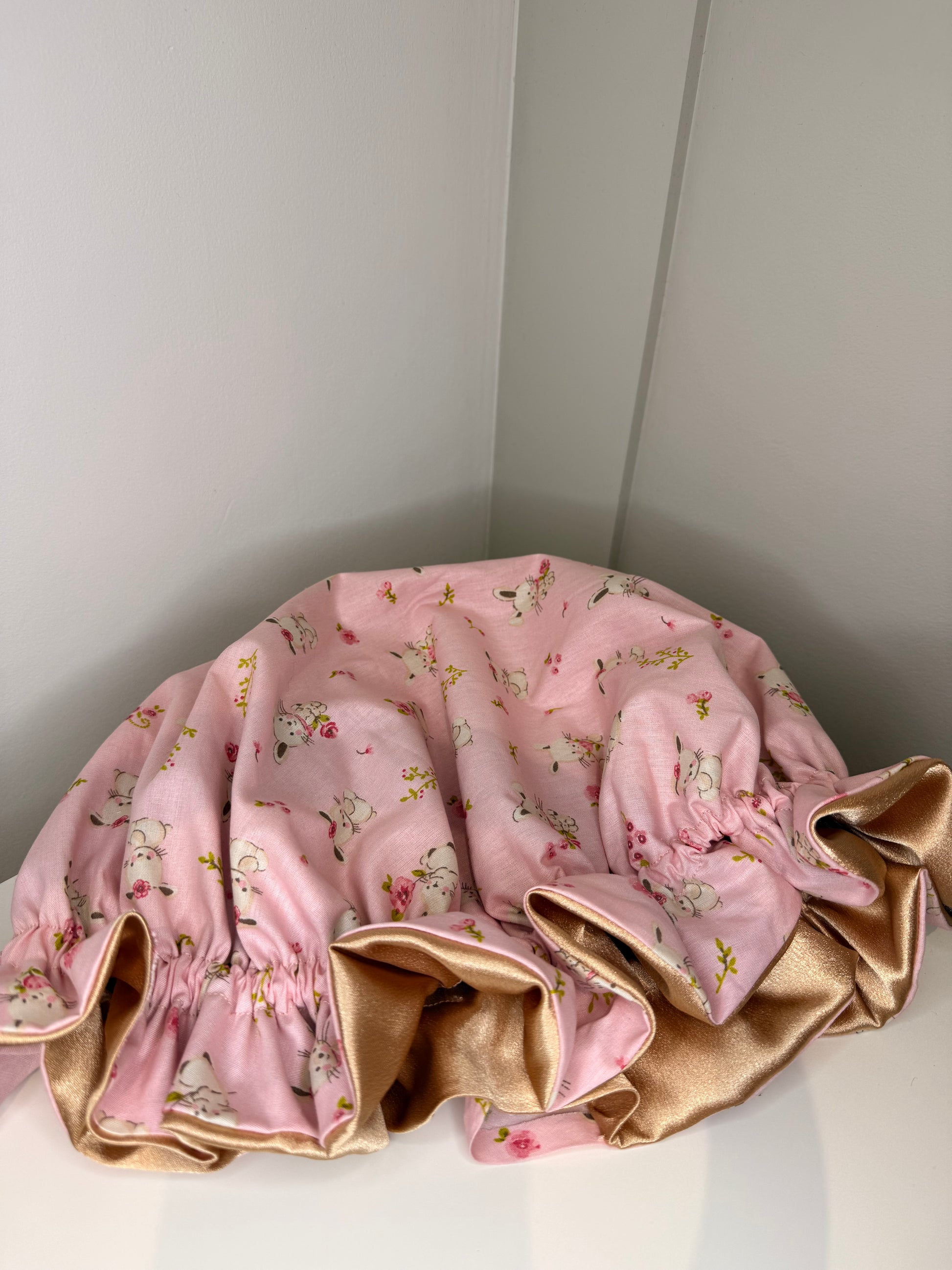 Pink floral bunny print bonnet with gold satin lining  on a white surface
