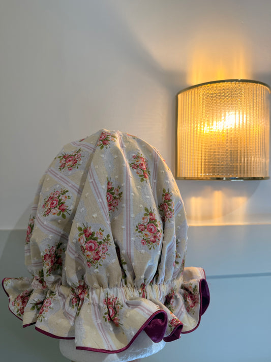 Floral-patterned satin sleep cap on a white surface with a lamp in the background