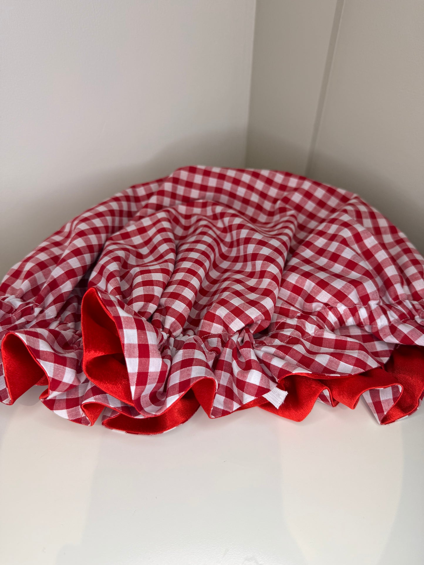 Red and white checkered fabric bonnet on a white surface, showing the adjustable toggle 