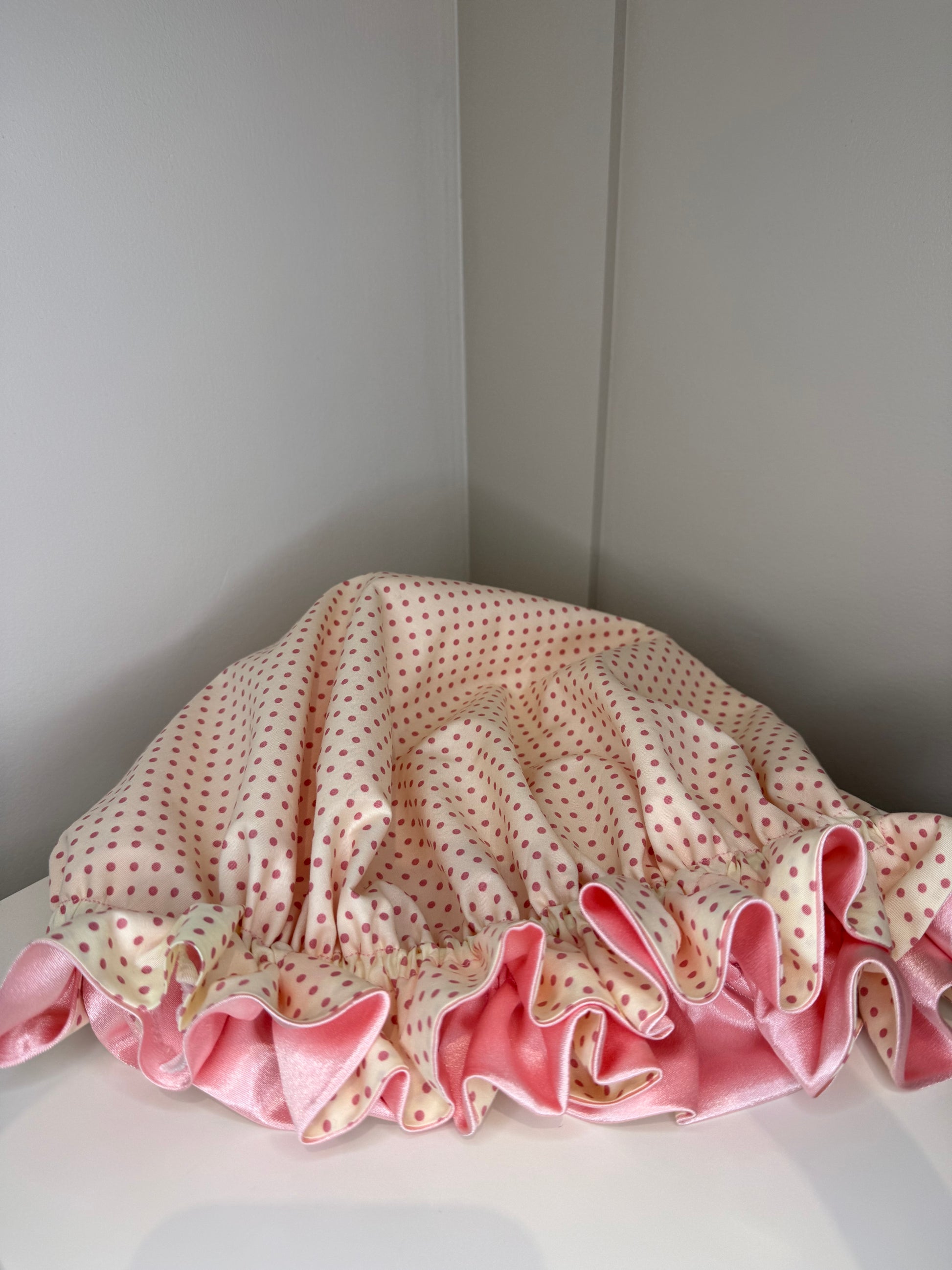 Pink and white polka dot sleep cap on a white surface