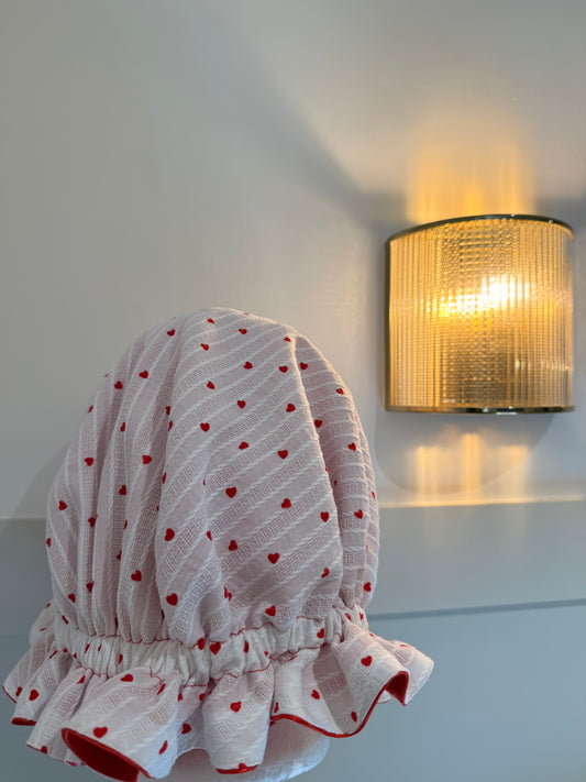 High-quality satin bonnet, with a textured material with small hearts on top of cherry red satin, crafters beautifully into a bonnet 