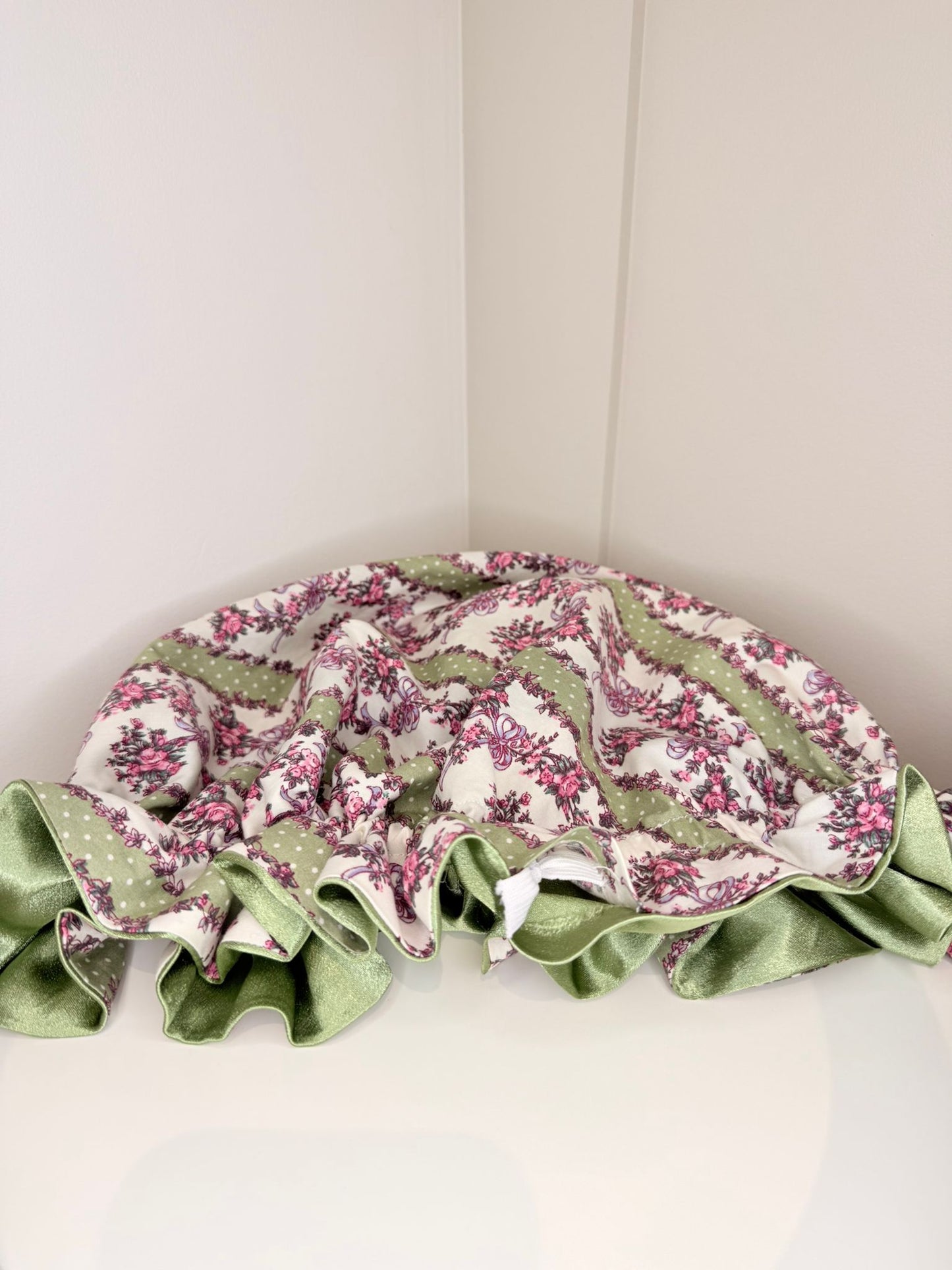 Floral patterned bonnet with green satin on a white background. Made in the UK