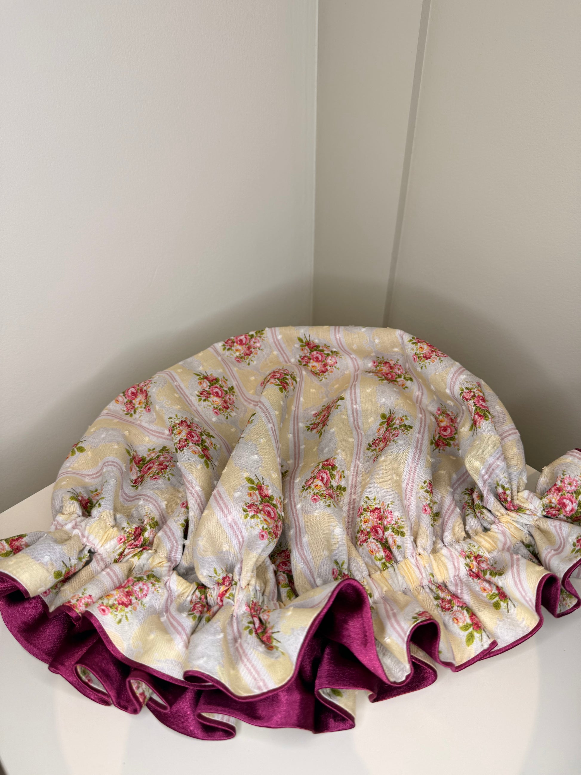Floral patterned bonnet with ruffled edge on a white surface