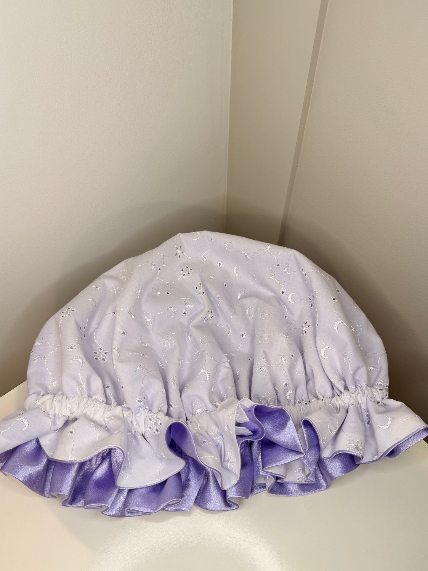 Purple and white bonnet with decorative ruffles on a light background