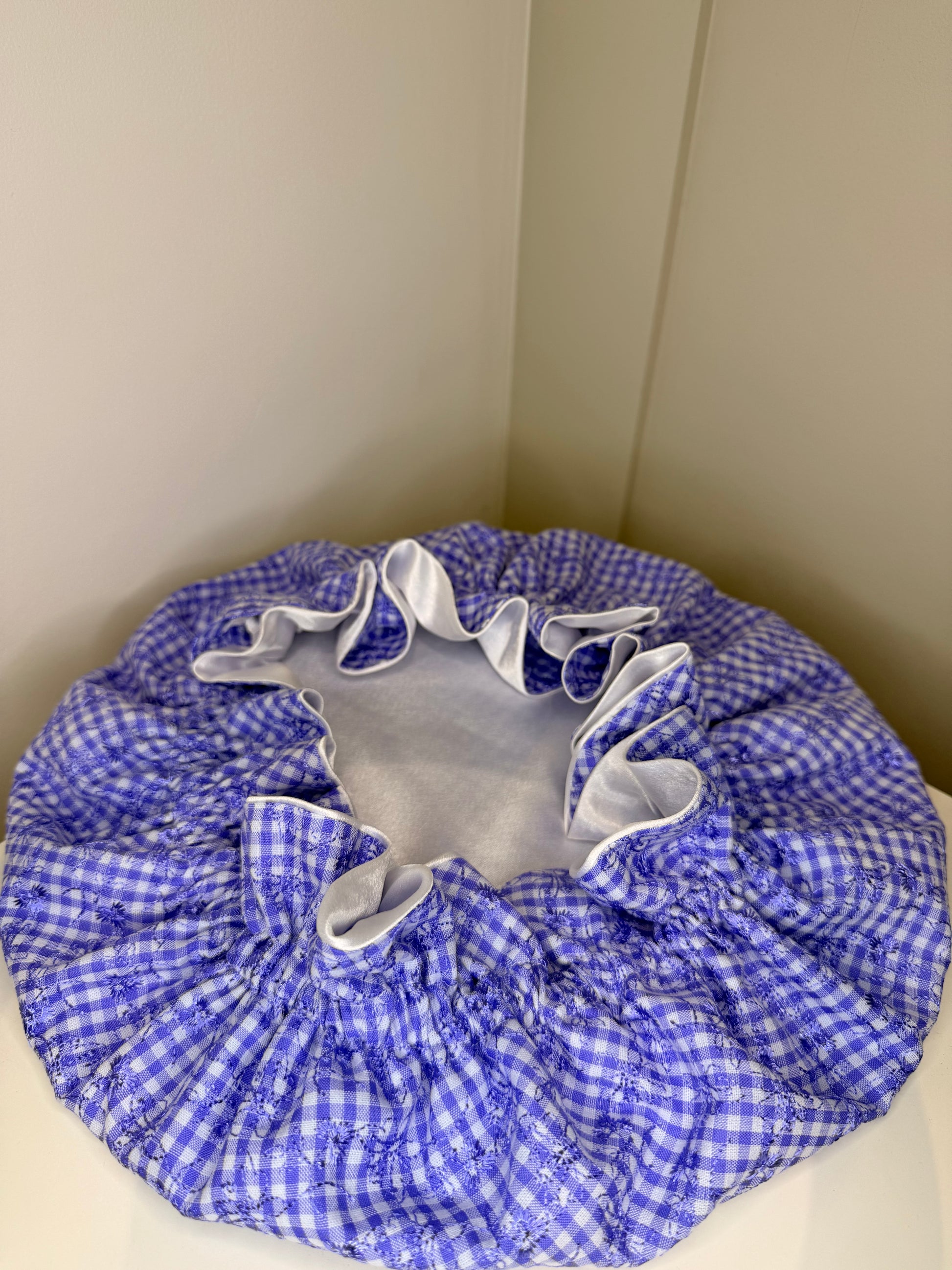 white and purple gingham satin cap on a beige surface