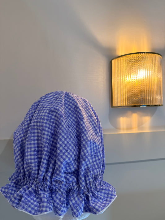 periwinkle and white checkered sleep cap on a light gray wall with a light fixture.