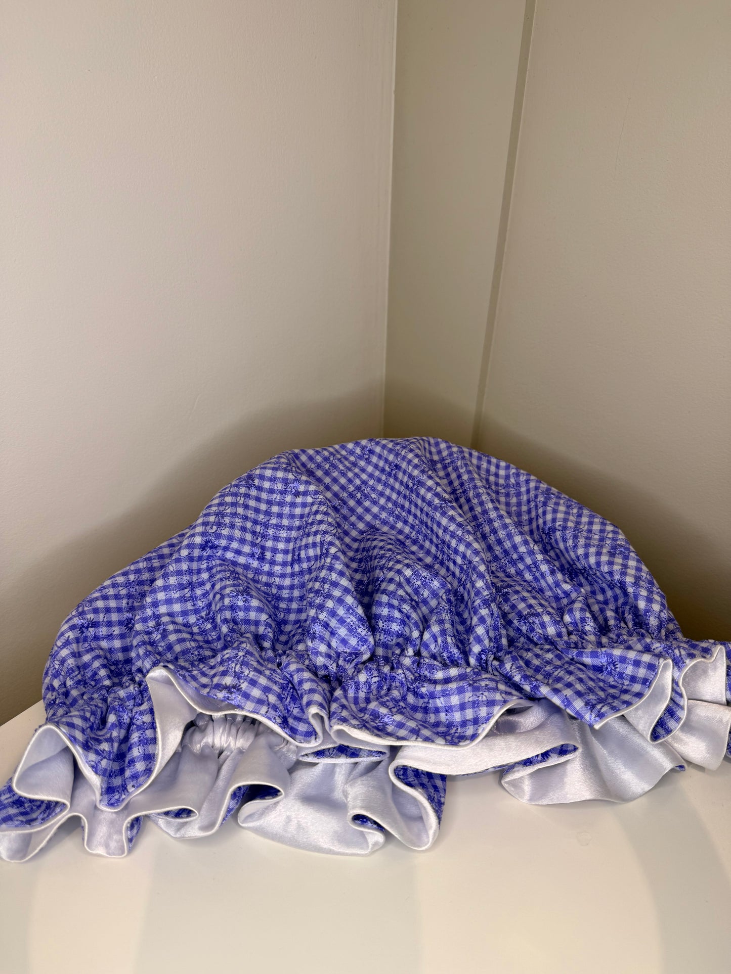 lilac and white checkered satin sleep cap on a beige surface