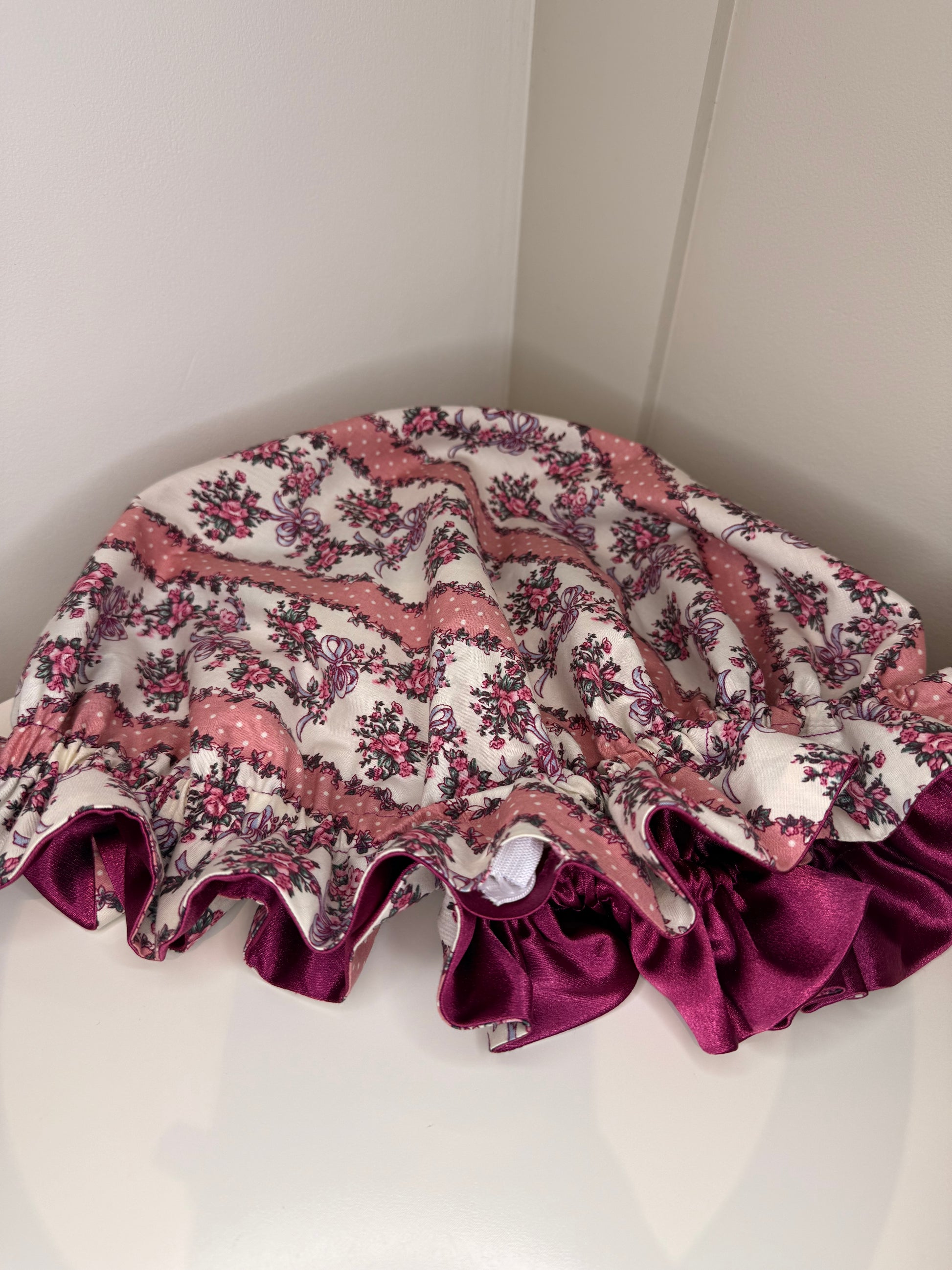 Floral patterned adjustable satin sleep cap with ruffled edge on a white background