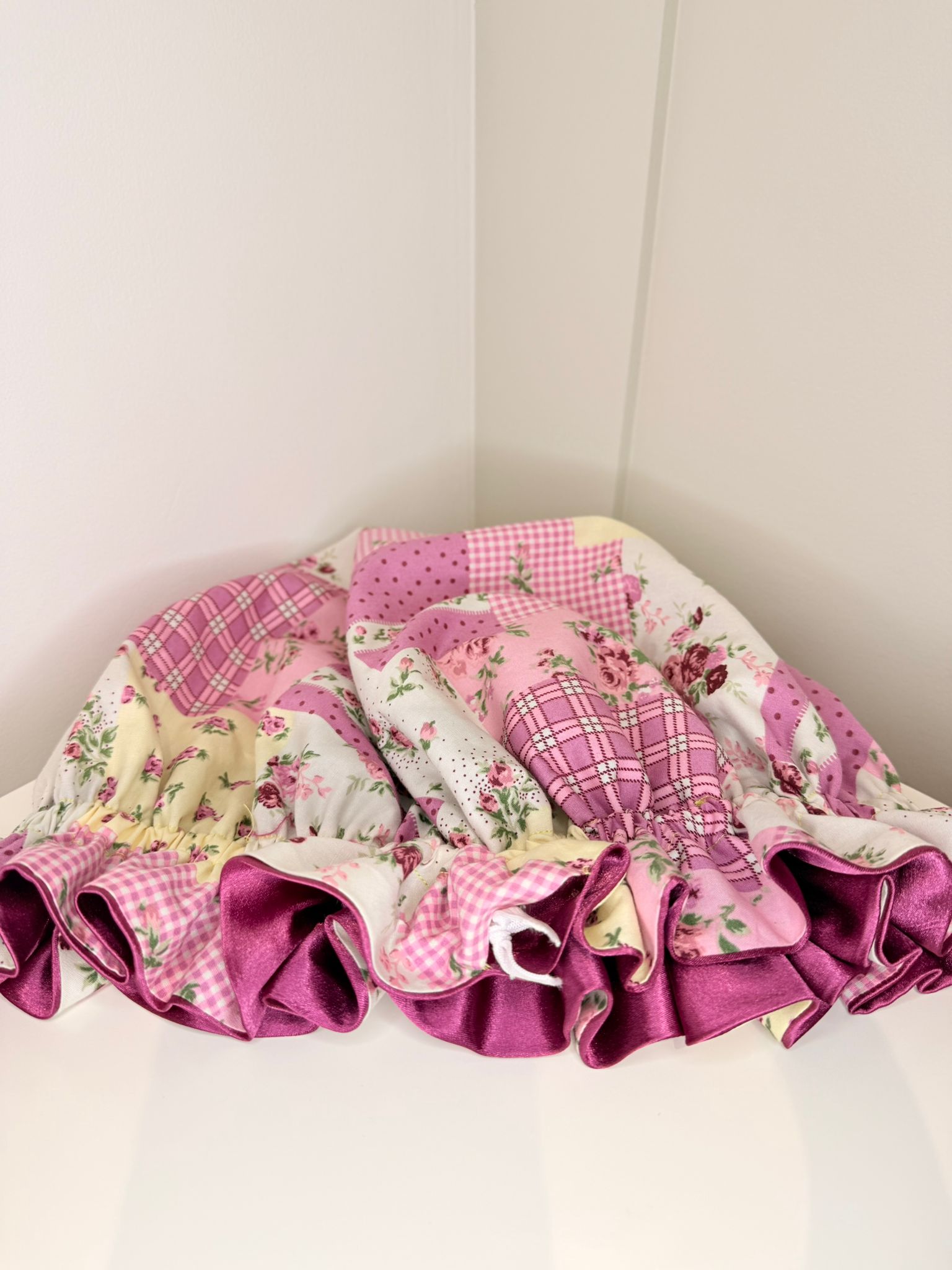 Pink and floral patwork fabric bonnet with ruffled edges on a white background