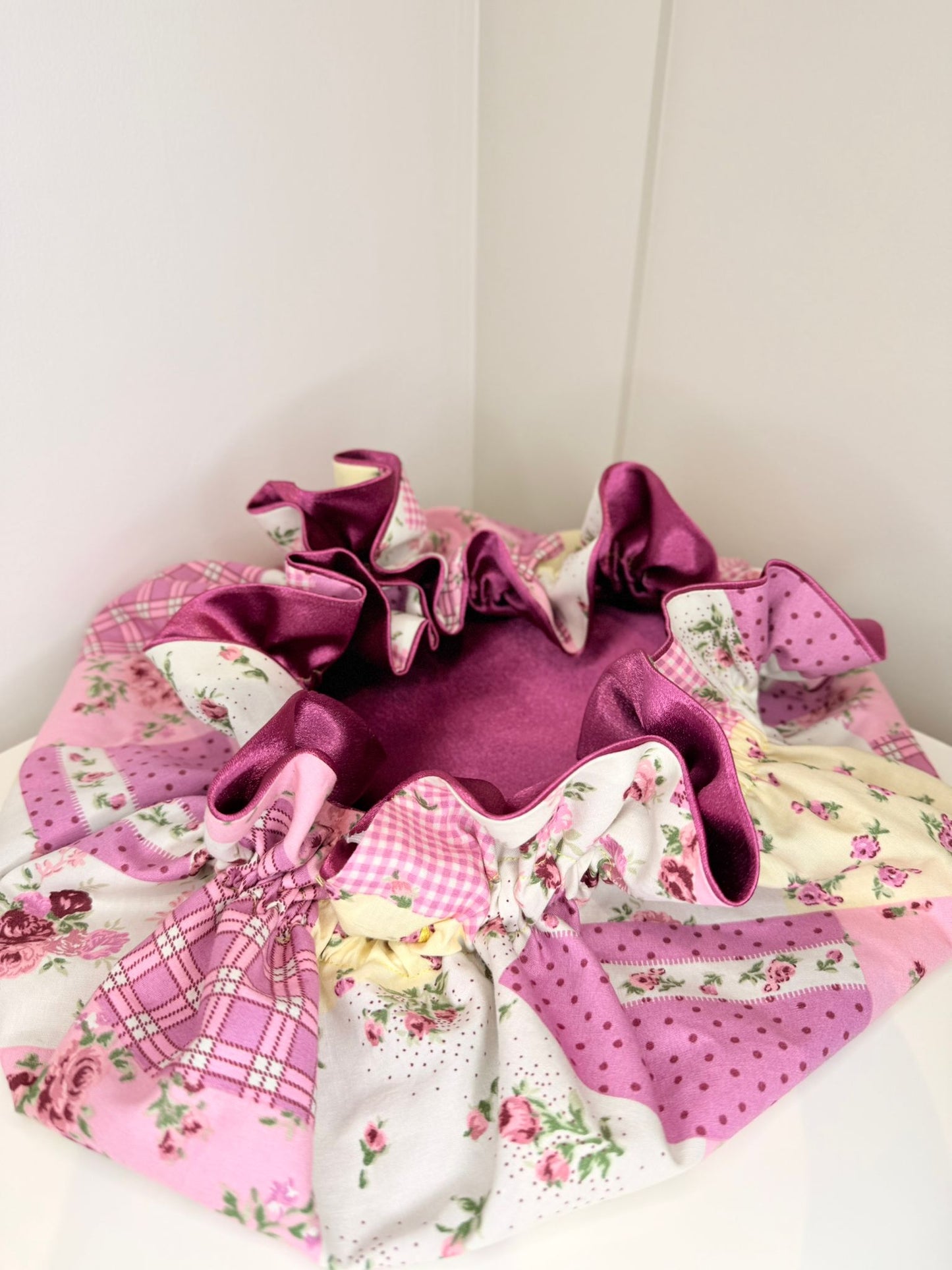 Pink and purple fabric bonnet with floral patterns on a white background